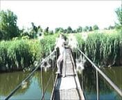 Summer nostalgia. Dressed in sun. Sexy naked woman MILF walks on hanging bridge of river. Nudists. Naturists. Nude beach. Music erotic clip. from walking nude woman
